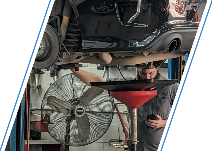 Technician draining engine oil from a vehicle on a lift during routine maintenance.