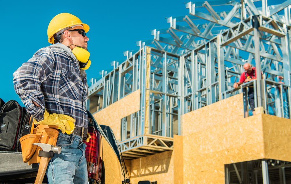 A Construction Worker Is Standing in Front of A Building Under Construction — Hager Surveying In Mullumbimby, NSW
