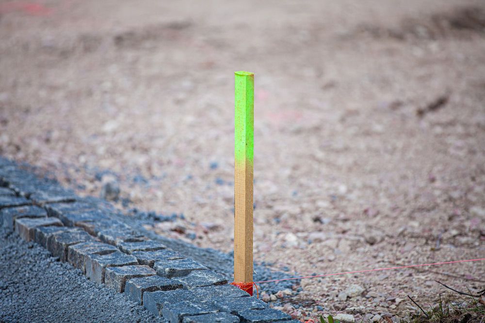A Wooden Pole with A Green Marker on It Is Sitting on The Ground — Hager Surveying In Banora Point, NSW