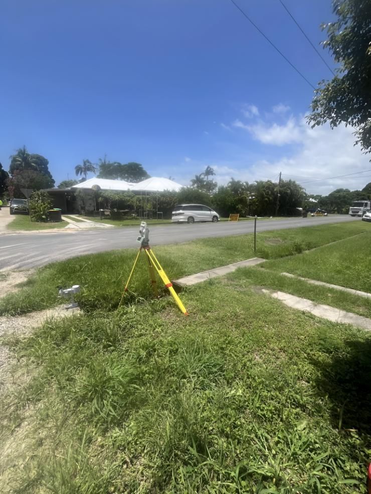 Tripod is Sitting in the Grass in Front of a House — Hager Surveying In Currumbin, QLD