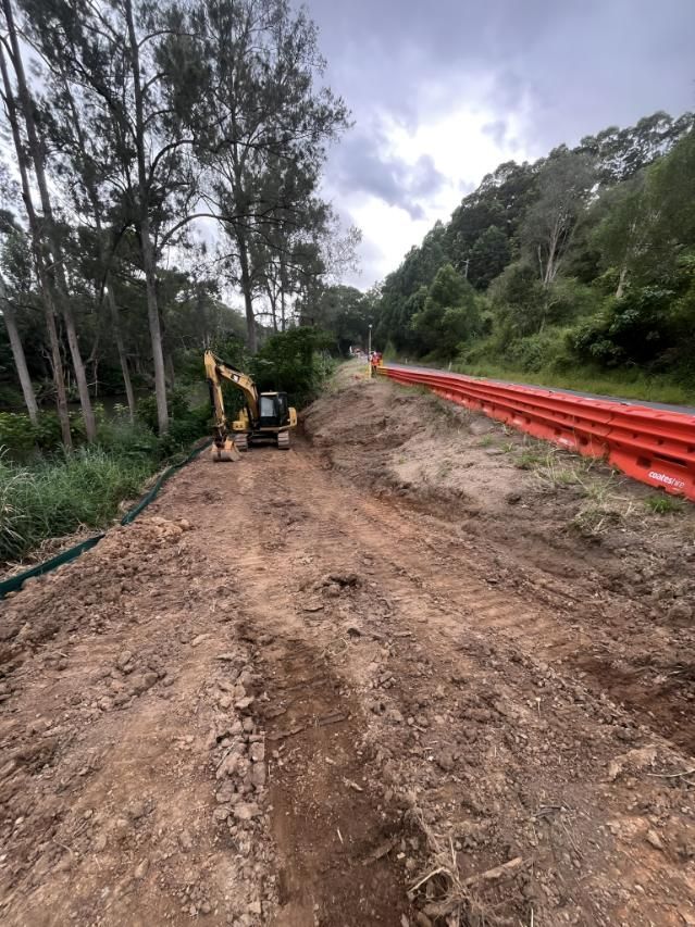Yellow Excavator is Sitting on the Side of a Dirt Road — Hager Surveying In Bangalow, NSW