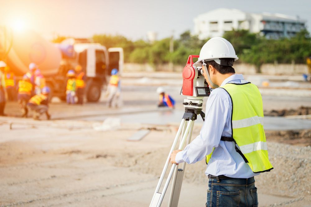 A Construction Worker Is Using a Theodolite on A Construction Site — Hager Surveying In Lismore, NSW