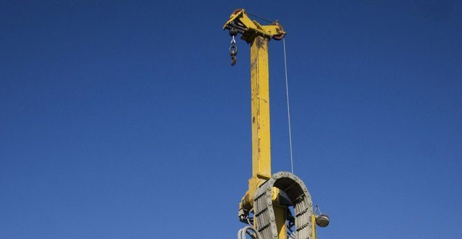 A Yellow Crane Is Lifting a Large Object Against a Blue Sky — Hager Surveying In Burleigh Heads, QLD
