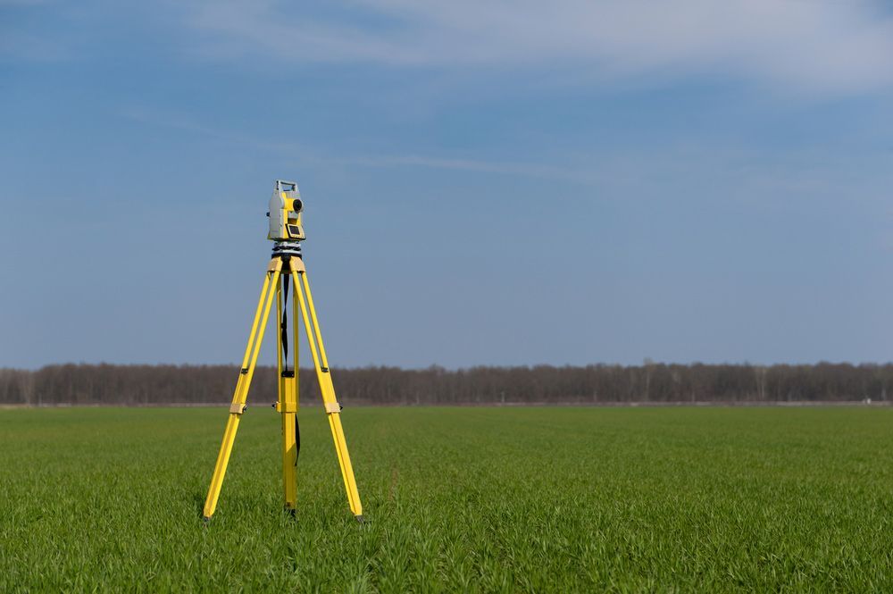 A Yellow Tripod Is Sitting in The Middle of A Grassy Field — Hager Surveying In Byron Bay, NSW