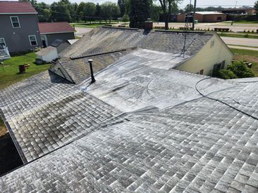 Roof of a house with visible algae and cleaning marks, showing contrast between treated and untreated areas.