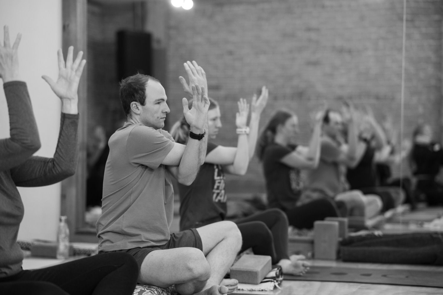 A group of people are sitting on the floor with their hands in the air.
