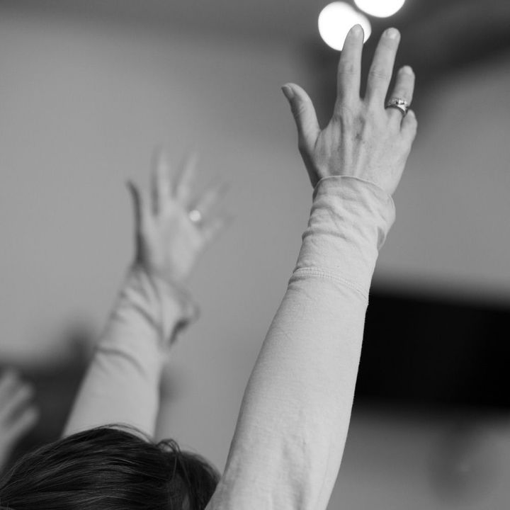 A woman with a ring on her finger is raising her hands in the air