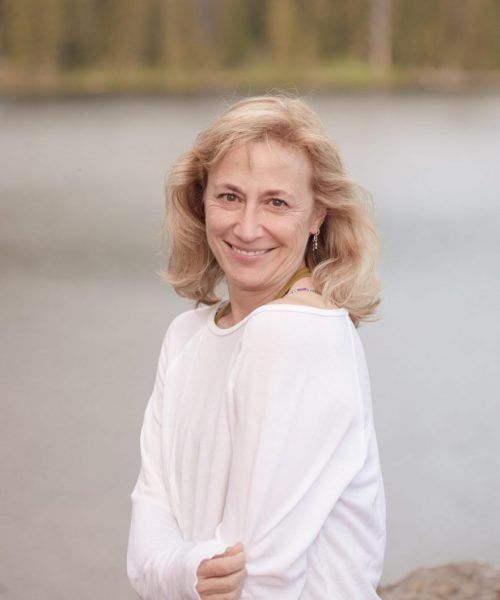 A woman is sitting on a yoga mat in front of a brick wall.