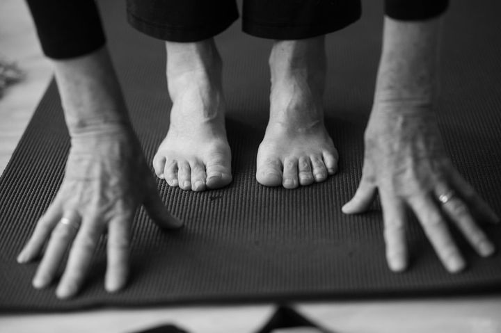 A black and white photo of a person 's feet and hands on a yoga mat.