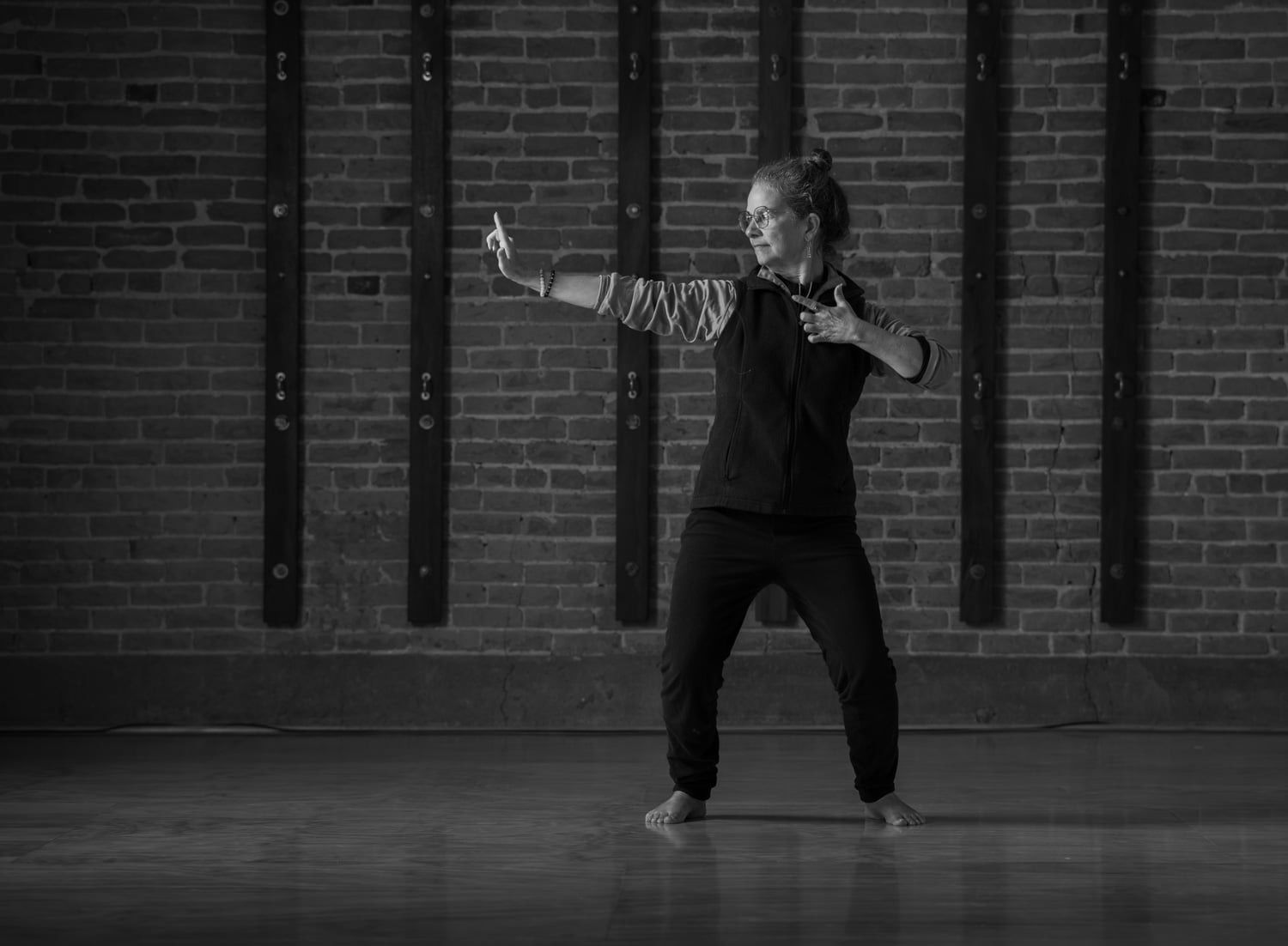 A woman standing next to a black and white dog in the snow