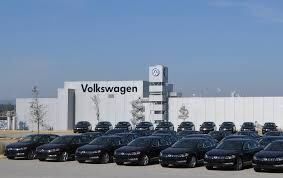 A row of black cars are parked in front of a volkswagen dealership.