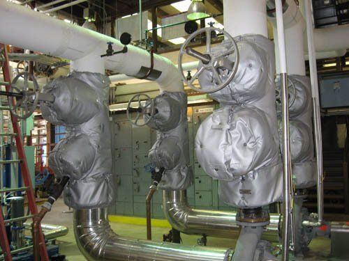 A factory with a lot of pipes and valves covered in blankets.