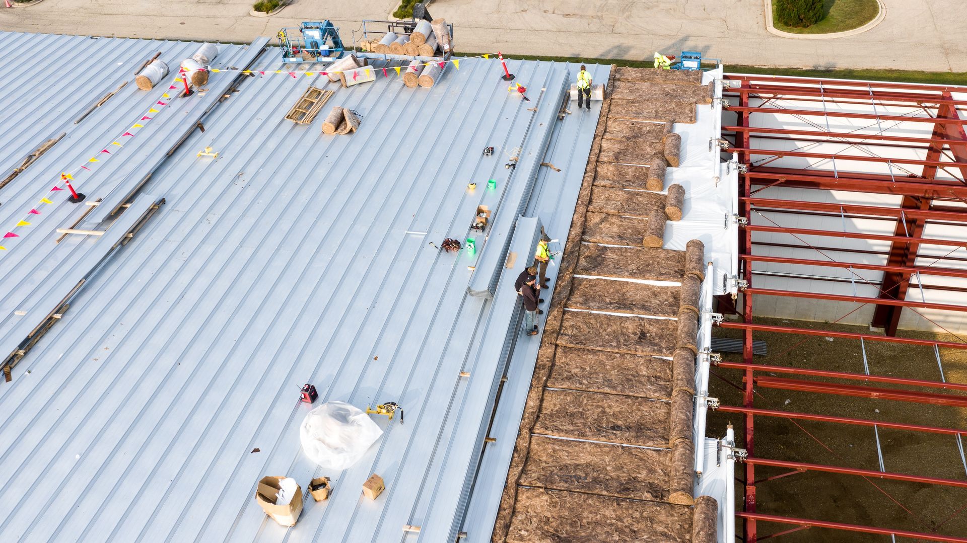 An aerial view of a building under construction with workers on the roof.