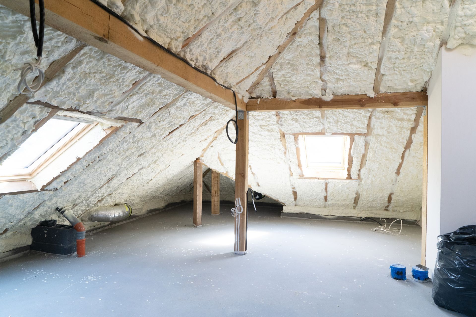 An empty attic with foam insulation and a window.
