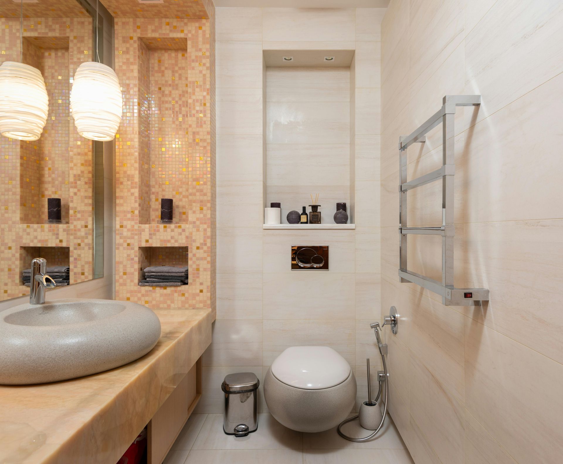 A modern, beige-toned bathroom with a stone sink, wall-mounted toilet, recessed shelving, and a metal towel warmer.