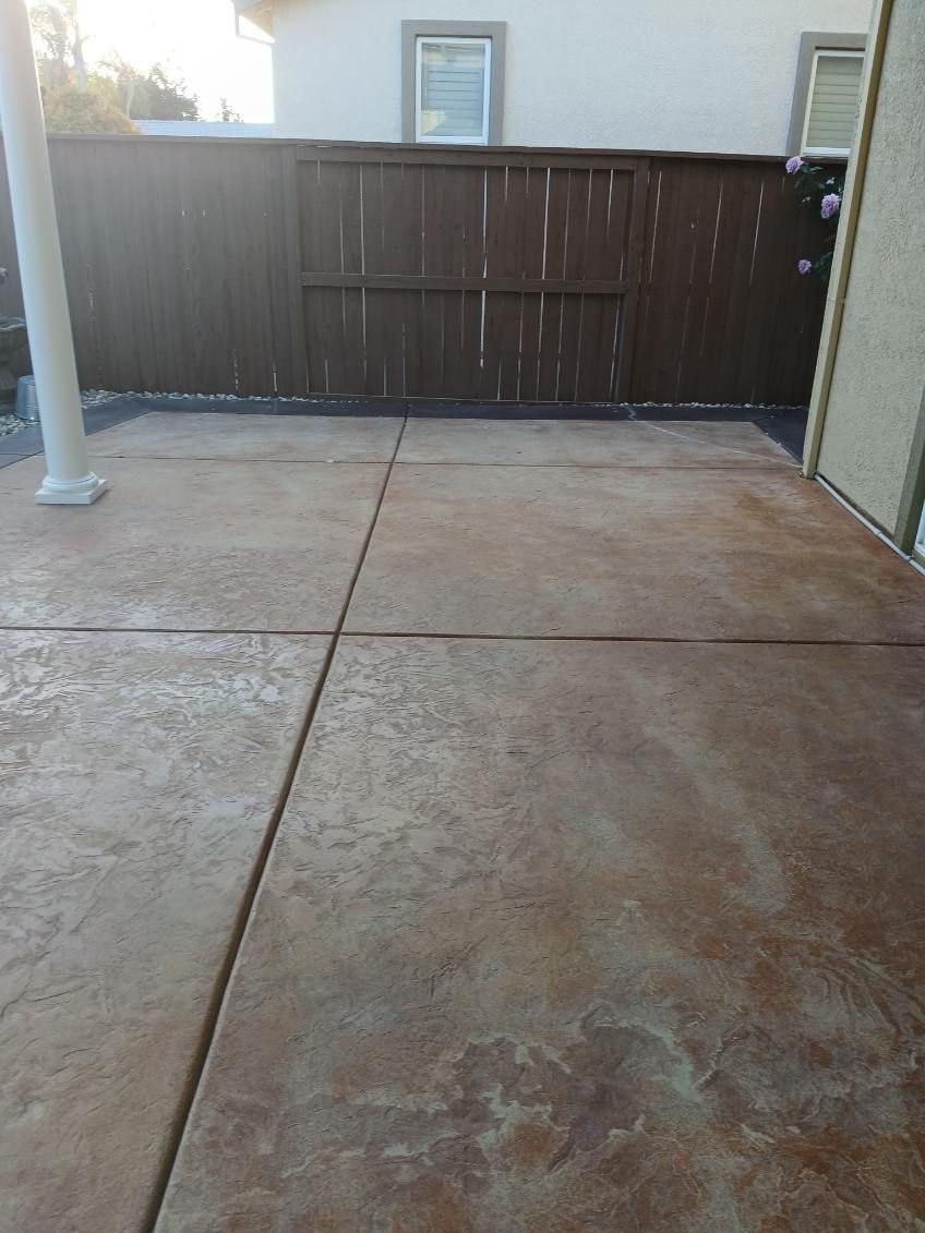 A concrete patio with a wooden fence in the background.