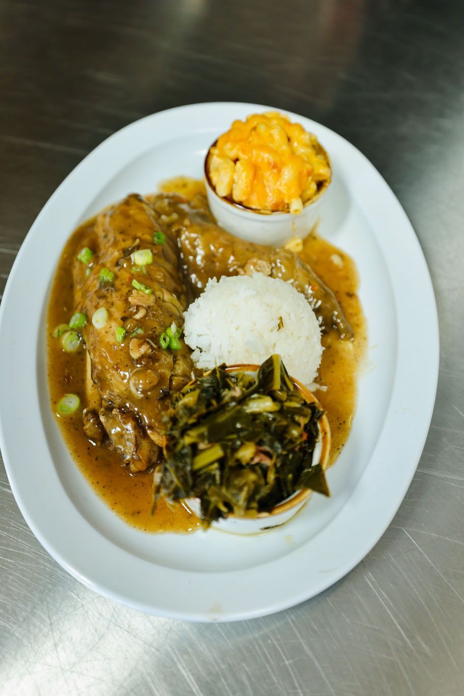 A white plate topped with meat , rice , green beans and macaroni and cheese.