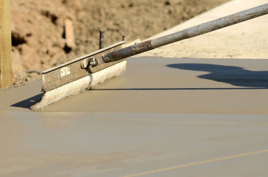 A person is using a trowel to spread concrete on a sidewalk.