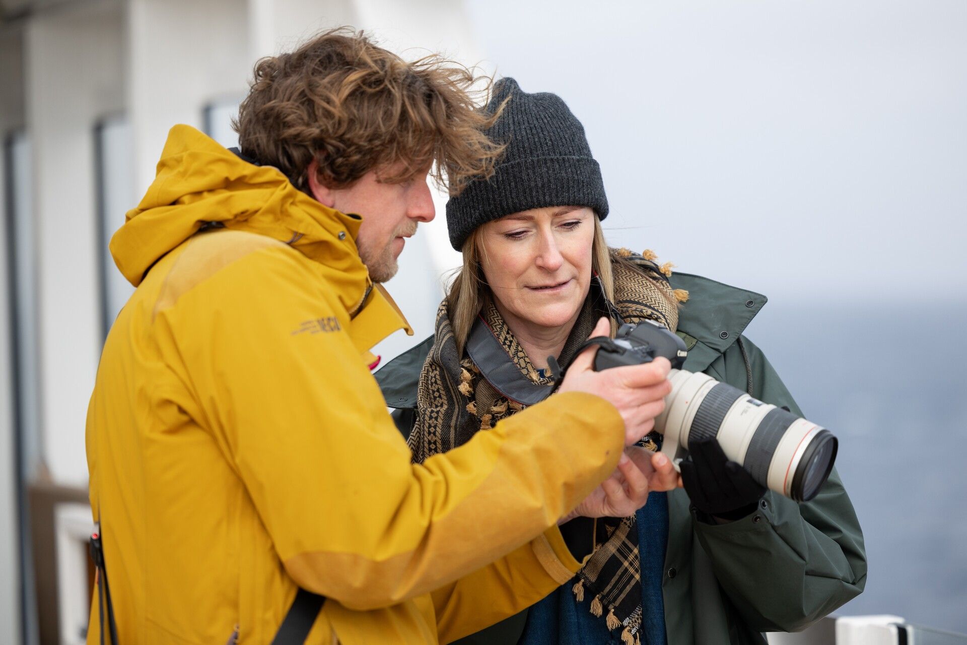 Een man en een vrouw kijken naar een camera.