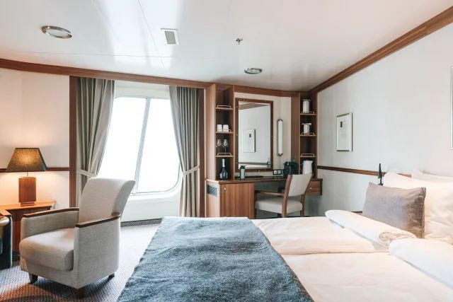 Een hotelkamer met een bed, stoel, bureau en spiegel.