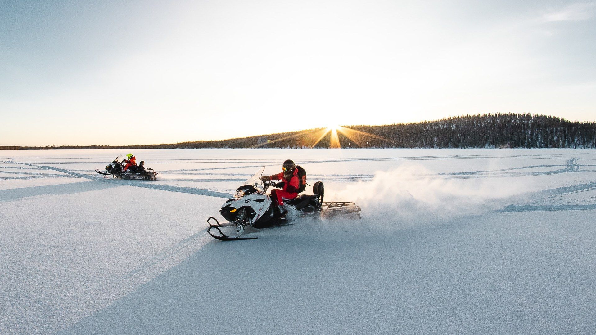 Een groep mensen rijdt op sneeuwscooters op een bevroren meer.