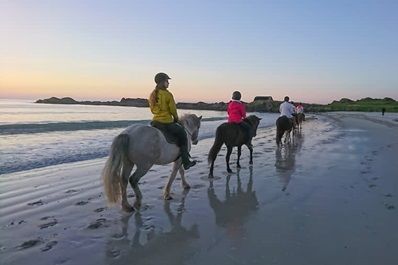 3 mensen te paard op het strand van de Lofoten, Noorwegen