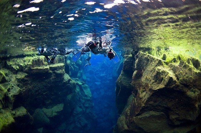 Een groep mensen zwemt onder water in een grot.