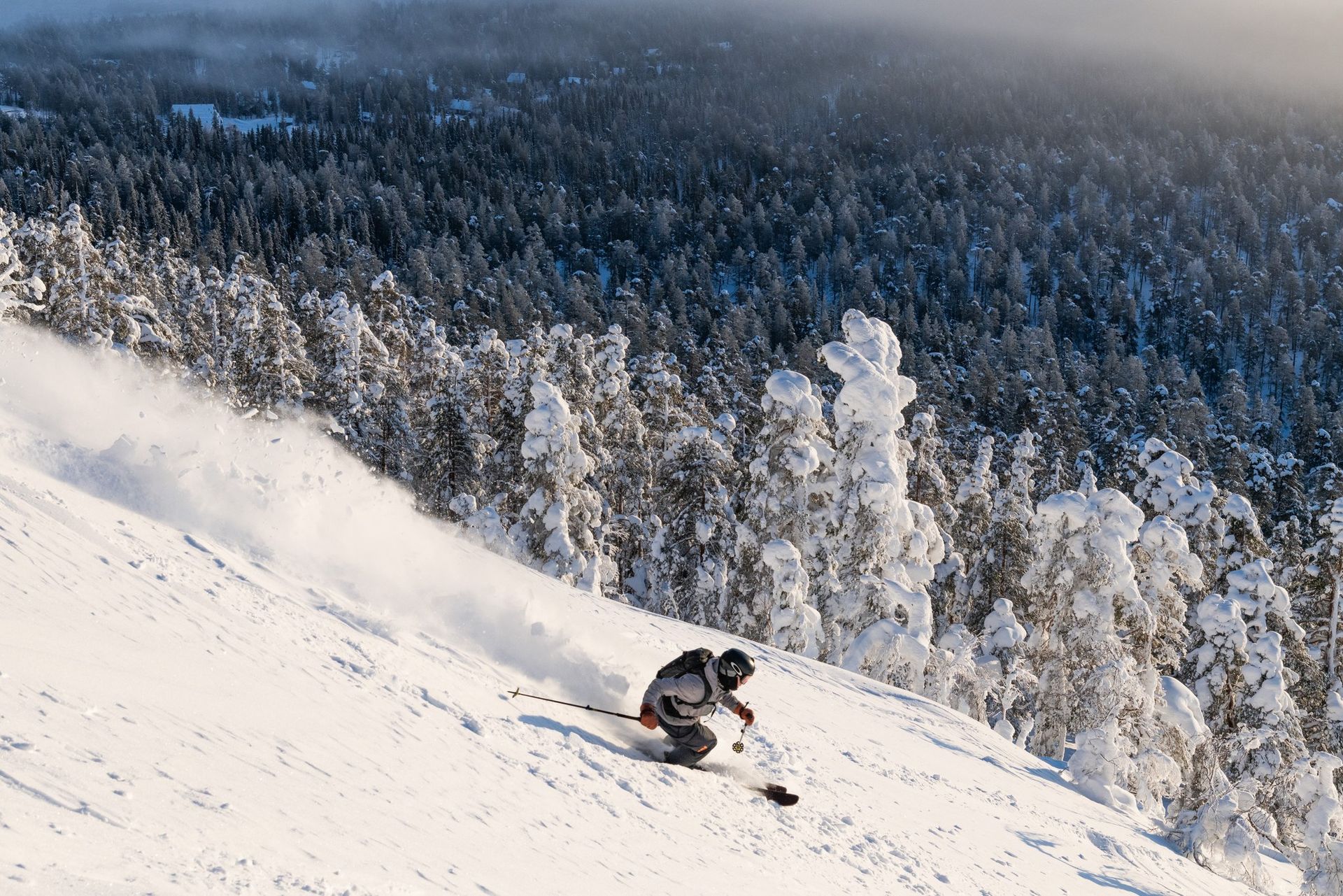 iemand is aan het skiën op een met sneeuw bedekte helling met bomen op de achtergrond.