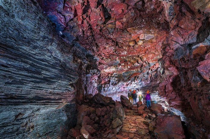 Een groep mensen loopt door een grot vol stenen.