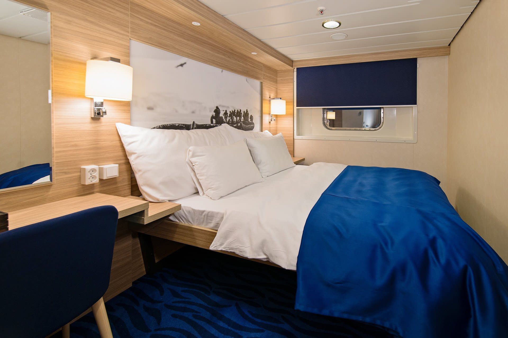 Een slaapkamer op een cruiseschip met een bed en een bureau.