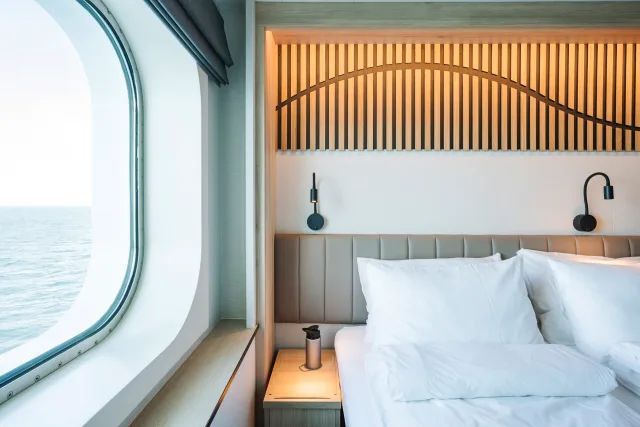 Een hotelkamer met een bed en een raam met uitzicht op de oceaan.