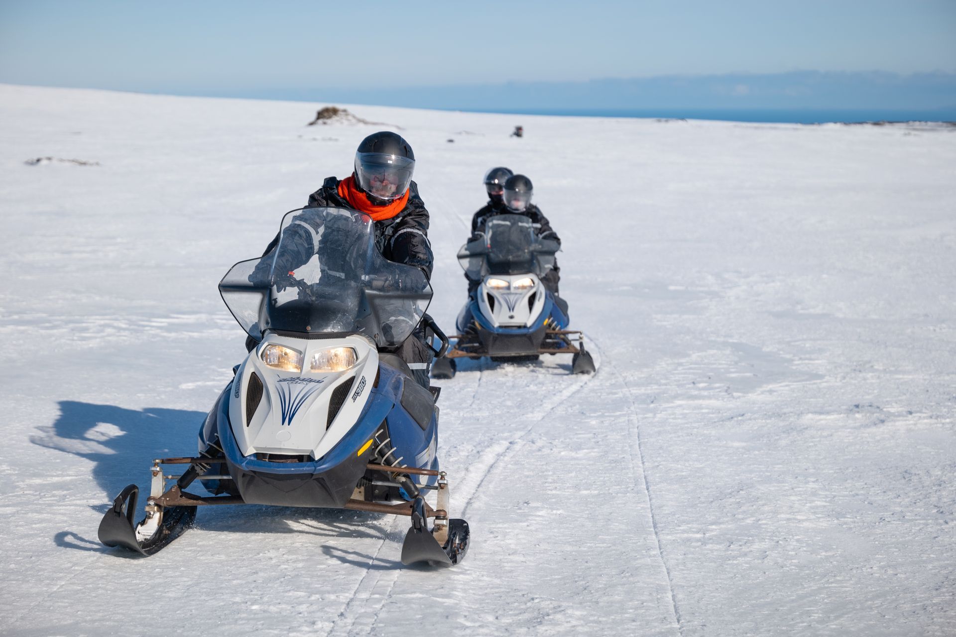 Een groep mensen rijdt op sneeuwscooters in de sneeuw.