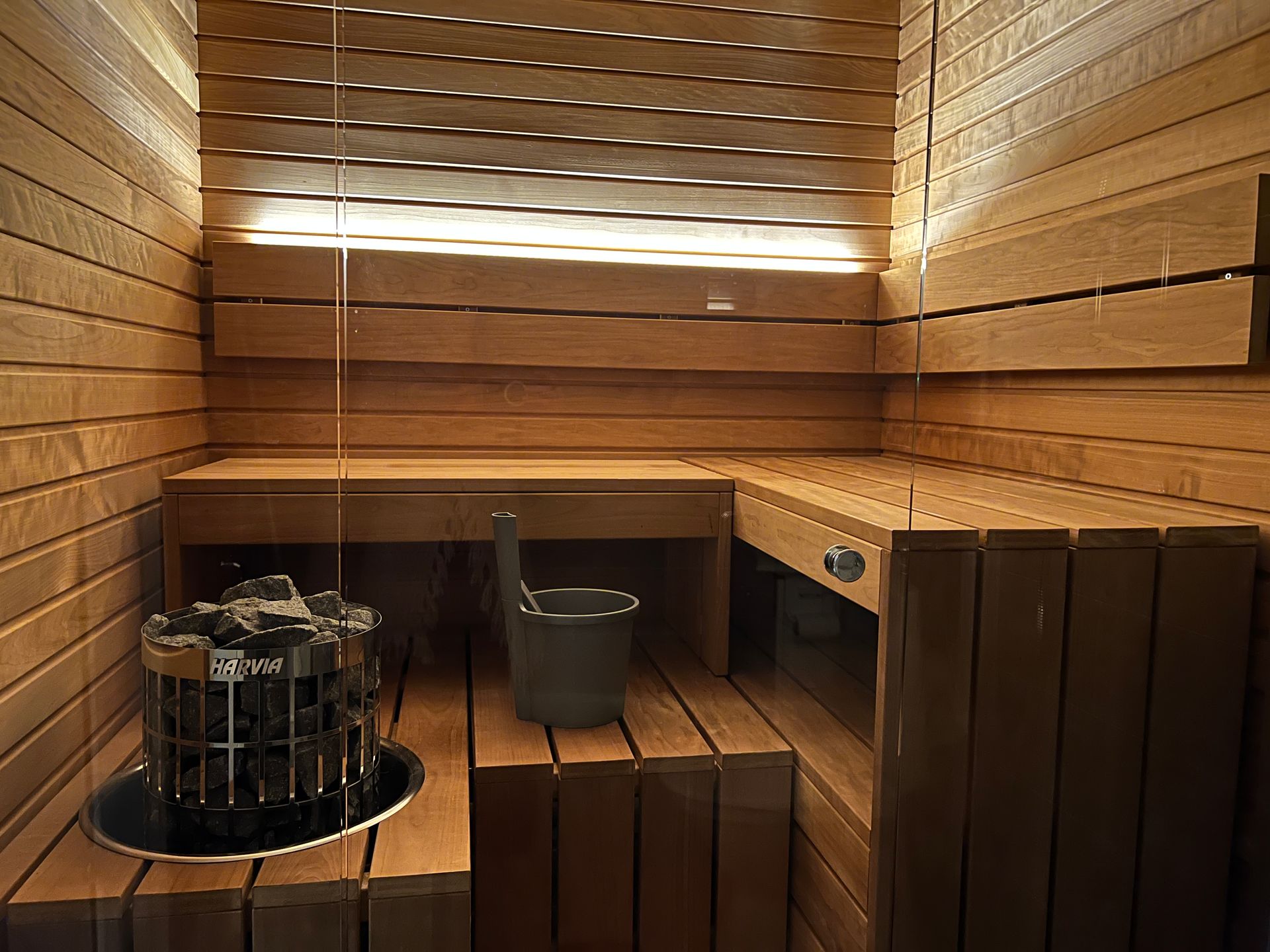 Een kleine houten sauna met emmer en kachel.
