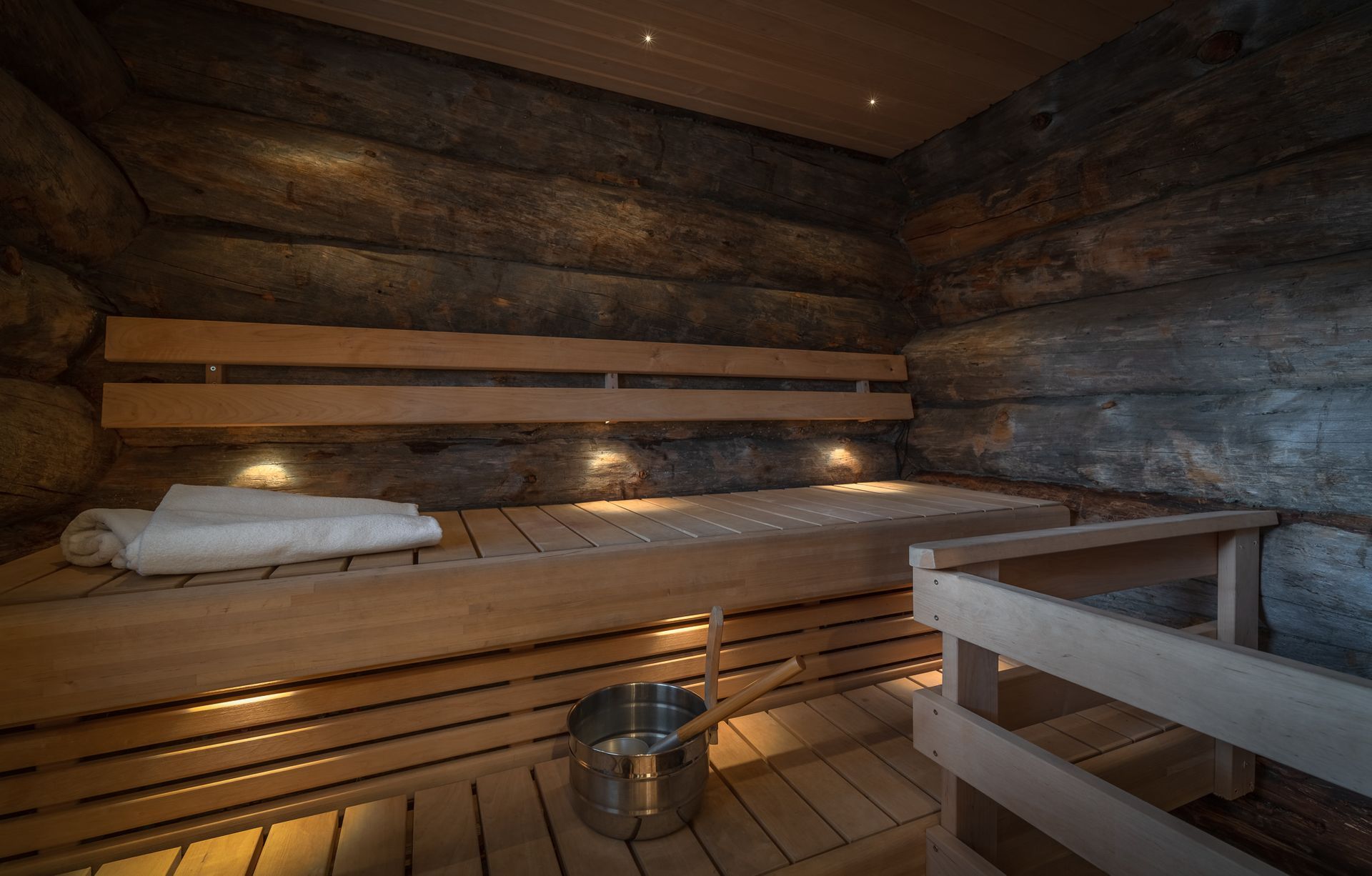 Een houten sauna met een emmer en een handdoek op de bank.