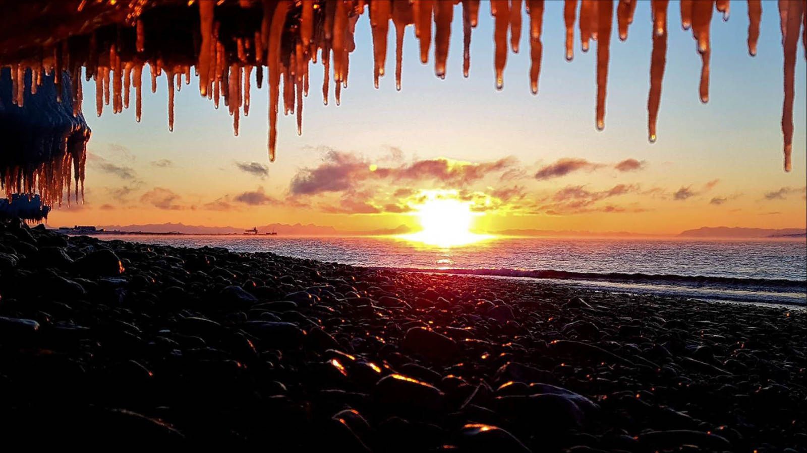 De zon gaat onder boven de oceaan en er hangen ijspegels aan het plafond.