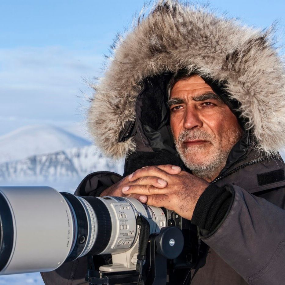 Een man met een bontkap houdt een camera vast