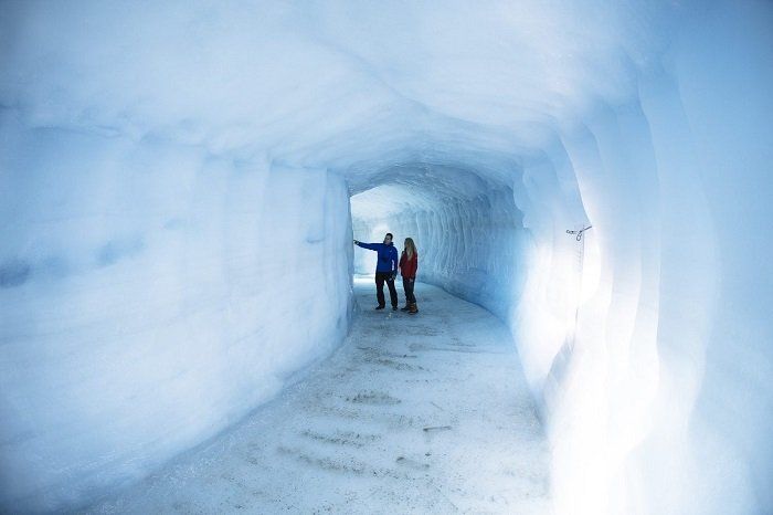 Een man en een vrouw staan ​​in een tunnel van ijs.