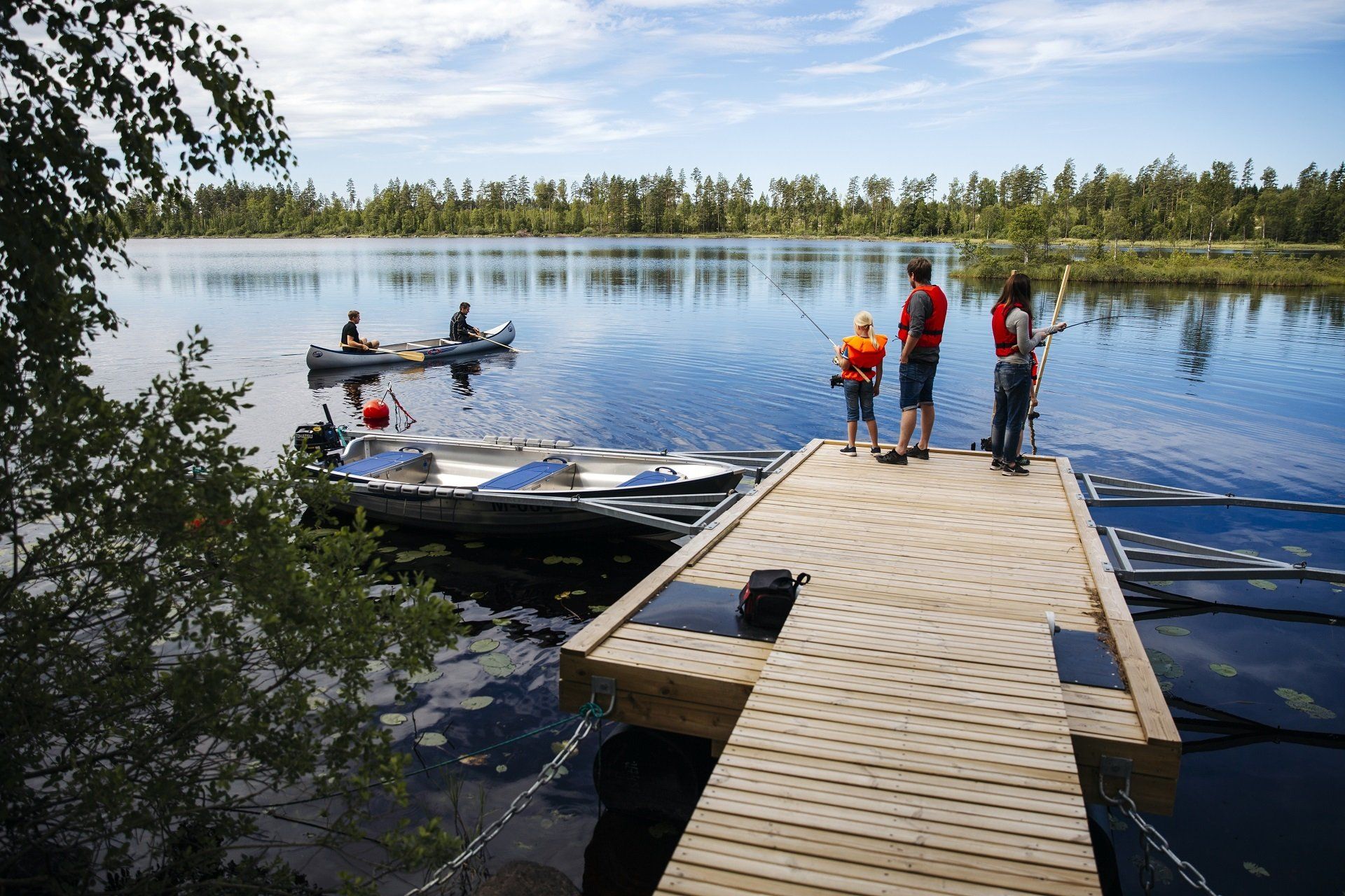 mensen aan het vissen en in een kano tijden hun zomervakantie in Zweden