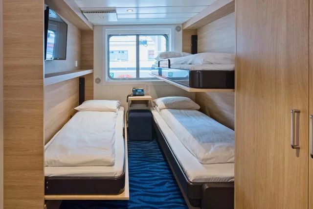 Een kamer met twee bedden en een raam op een cruiseschip.