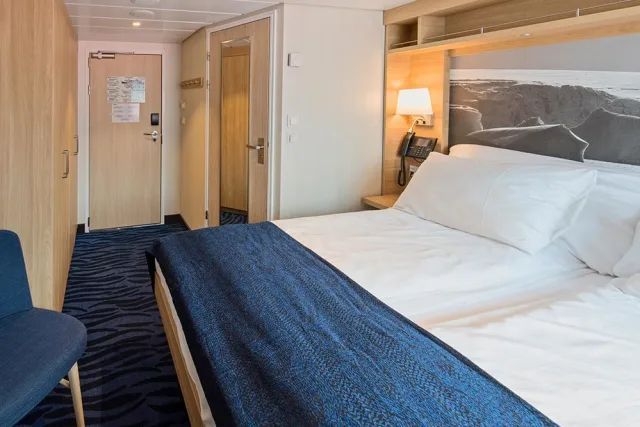 Een hotelkamer met een groot bed en een stoel.