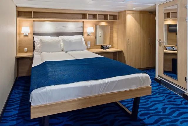 Een slaapkamer met een groot bed en een blauw tapijt.