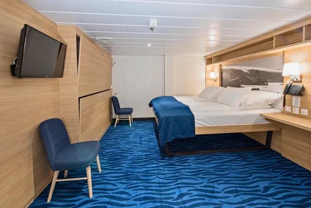 Een hotelkamer met twee bedden, een stoel, een televisie en een blauw tapijt.