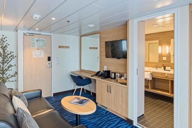 Een woonkamer op een cruiseschip met een bank, tafel en televisie.