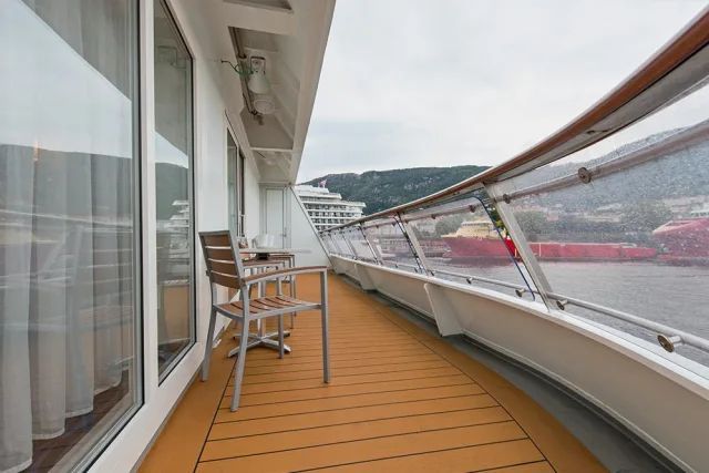 Een balkon op een cruiseschip met een stoel en een tafel.