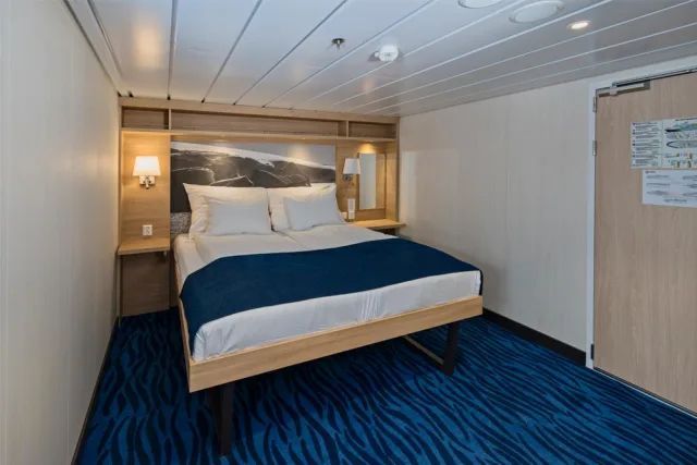 Een hotelkamer met een bed en een blauw tapijt.