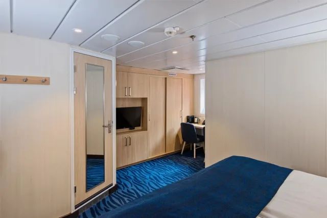 Een slaapkamer op een cruiseschip met een bed en een televisie.