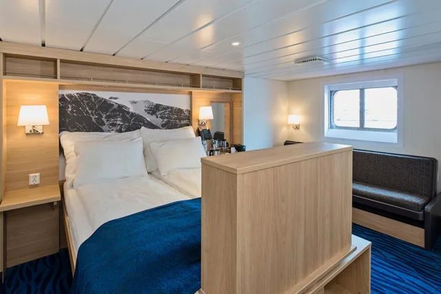 Een slaapkamer op een cruiseschip met een bed en een bank.