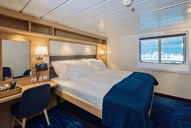 Een slaapkamer op een cruiseschip met een groot bed en een raam.