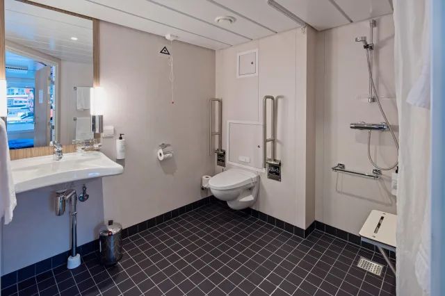 Een badkamer met wastafel, toilet, douche en spiegel.