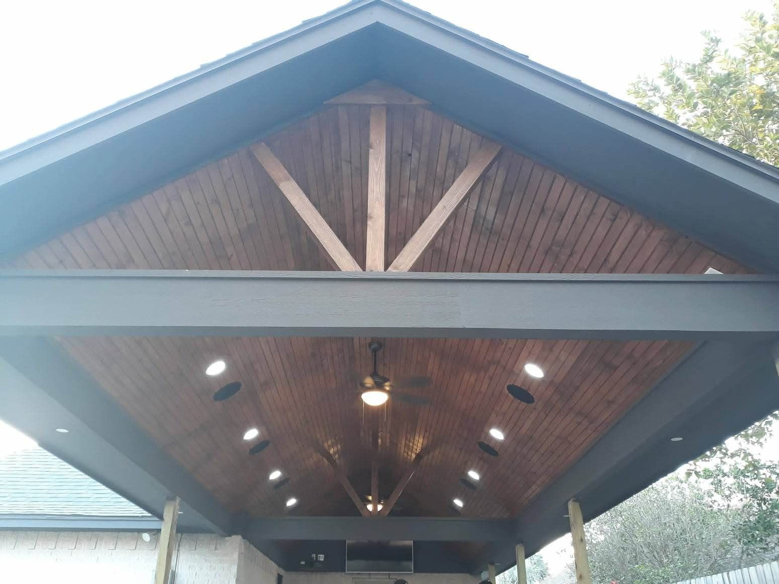 Dark wood and gray covered patio with recessed lighting, and a ceiling fan.